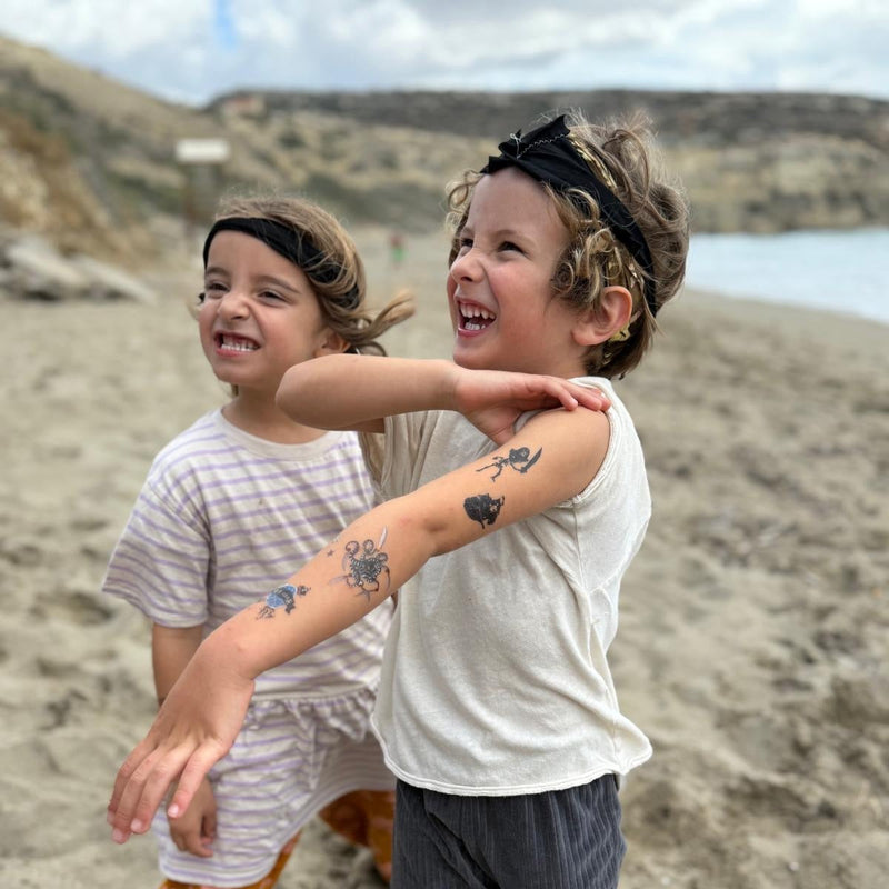 Two children playing on a sandy beach with a scenic background.